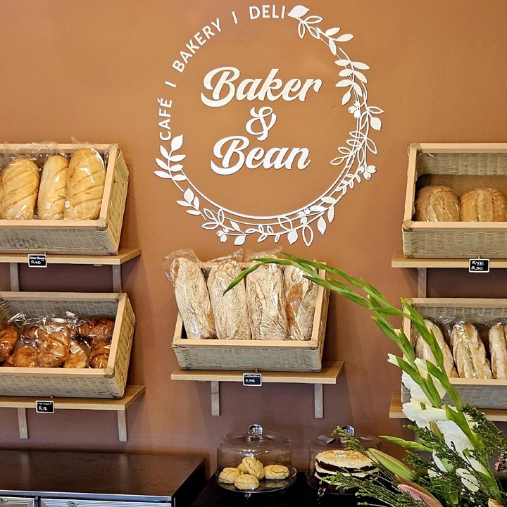 Fresh breads and pastries on the bakery shelves under the Baker & Bean logo