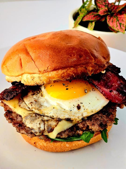 Burger with a fried egg, bacon and melted cheese at Baker & Bean café